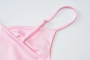 Detail view of adjustable straps and silky pink fabric on a bodycon dress