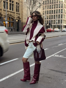 Street style shot of burgundy and beige turtleneck sweater with high leather boots