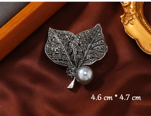 Macro shot of vintage leaf brooch with grey rhinestones and large round pearl detail
