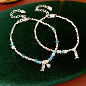 Detailed shot of silver bead bracelets with pearls and fish charms on green velvet