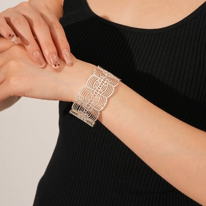 Detailansicht eines silbernen, ausgehöhlten breiten Manschettenarmbands am Handgelenk