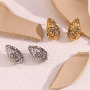 Detail of teardrop earrings with textured gold finish and crystal butterfly inlay