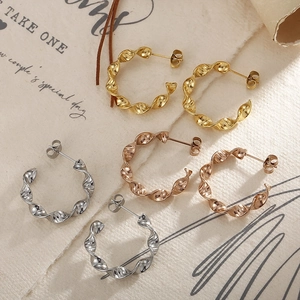 Detailed close-up of gold, rose gold and silver twisted hoop earrings on vintage paper