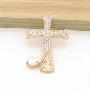 Close-up of golden cross pendant with sparkling rhinestones and drop-shaped crystal
