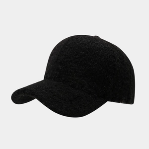 Close-up of thick black faux fur texture on a warm minimalist baseball cap surface