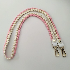 Close-up of pink and white woven bag strap with gold lobster clasps and leather ends