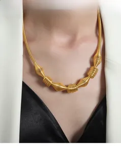 Macro shot of tiered gold plated titanium steel spiral necklace on white blazer