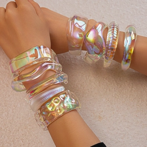 Close-up of stacked iridescent acrylic bangles with holographic finish on a female wrist