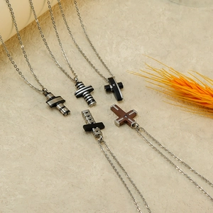 Collection of titanium steel cross necklaces with crystal accents on a stone surface
