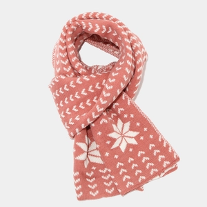 Detail of coral pink knit scarf with white snowflake jacquard pattern and thick texture