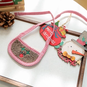 Close-up of reindeer plush pouch with wooden Merry Christmas and Welcome ornaments