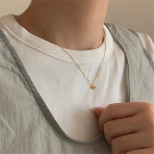 Close-up of golden knotted heart pendant necklace on collarbone with 925 silver chain