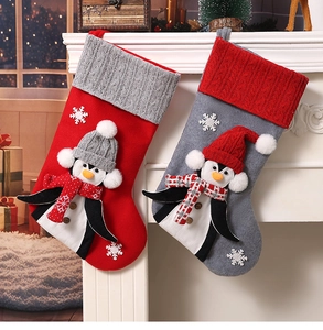 Detail of grey and red Christmas stockings with 3D penguin figures hanging on a fireplace
