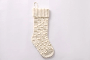Detailed view of white knitted Christmas stocking with unique fish scale textured pattern