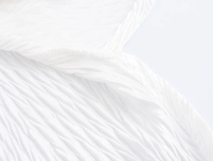 Macro shot of the white textured fabric and pleated detail of the women's button-up shirt