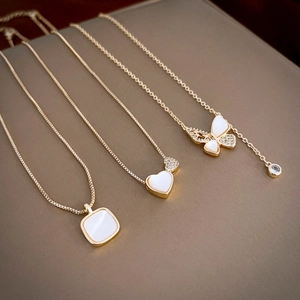 Detailed macro view of gold plated butterfly and heart pendants with white shells
