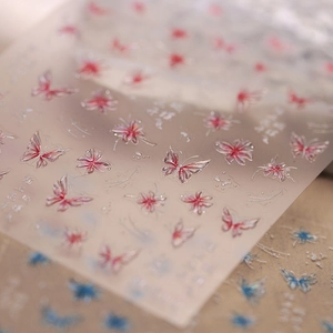 Detailed macro view of 5D embossed butterfly and flower nail stickers with water drop texture