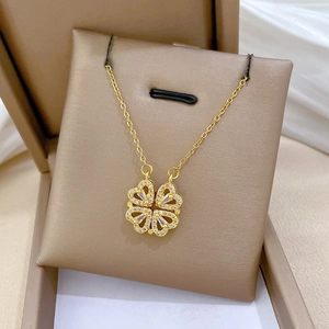 Macro shot of gold four-leaf clover necklace with heart-shaped crystal inlay in jewelry box