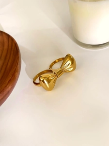 Macro d'une bague double doigt avec nœud doré poli sur fond blanc épuré avec décor