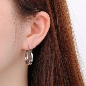 Close-up of double-loop silver titanium earrings worn by a model for a luxury look