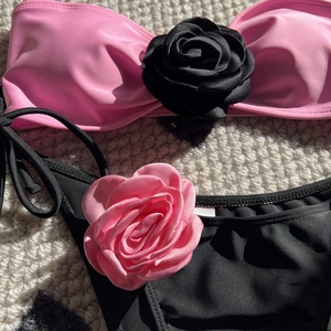 Detail of pink bandeau bikini top and black bottoms featuring 3D floral rose accents