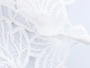 Detailansicht der weißen Spitzenstickerei mit hohlem Netz und Blumenmuster auf Kleid