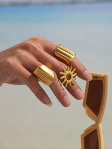 Detail showing stacked chunky gold square rings and sun motif ring on model finger