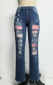 Dettaglio di jeans blu scuro strappati con paillettes rosa e toppe maculate leopardate