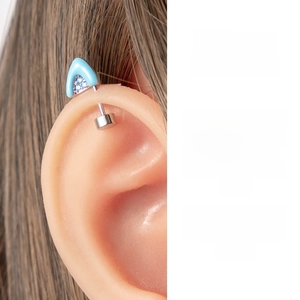 Detail of blue zircon cat ear tragus stud in titanium steel on person's ear cartilage