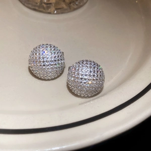 Macro shot of silver stud earrings with sparkling cubic zirconia pavé on ceramic plate