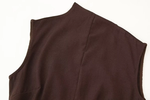 Detail of dark brown sleeveless dress with one-shoulder metal ornament and soft texture
