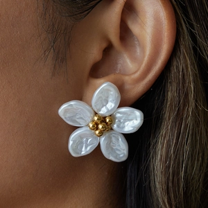 Close-up of elegant gold flower earrings featuring white baroque pearl petals and metal pistil