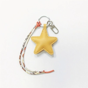 Detail of yellow star-shaped leather charm with patterned ribbon and silver metal clasp