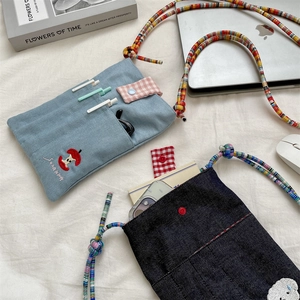 Close-up of cute embroidered denim crossbody bag with colorful rope straps and pockets.