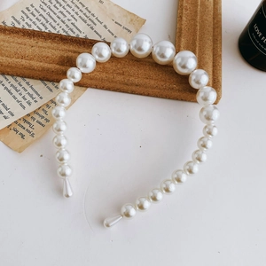 Detail showing gradient size white faux pearls on elegant hairband for wedding styling
