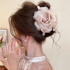 Detail of champagne pink mesh rose hair claw clip on model's elegant bun hairstyle