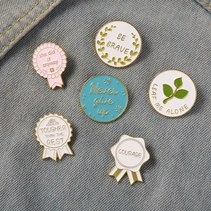 Set of six colorful enamel pins with inspirational quotes on blue denim fabric