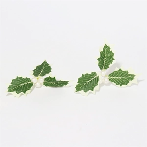 Close-up of artificial Christmas holly leaves with white berries and green-white gradient foliage
