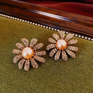 Macro shot of vintage daisy earrings featuring champagne gold petals and pink pearl centers