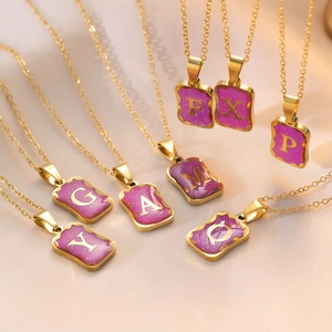 Gold titanium steel necklaces with purple square letter pendants on silk background