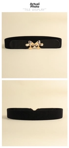 Detail of a black elastic waist belt for women featuring a golden butterfly buckle
