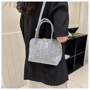 Grey felt shell bag with crocodile texture and gold hardware on a model's shoulder