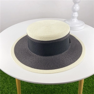 Detail view of two-tone woven boater hat featuring ivory crown and charcoal brim with black ribbon