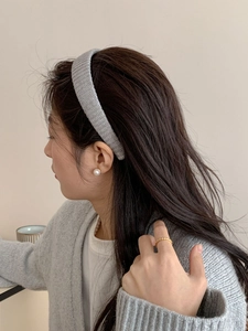 Détail d'un bandeau en tricot gris avec boucles d'oreilles perles et bague dorée
