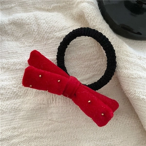 Detail of a red velvet bow hair tie with gold polka dots on a beige linen background