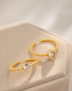 Detail of gold open rings with bead edge design and teardrop white zircon stones