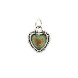 Macro shot of silver heart pendant with green glitter inlay and beaded metal edges