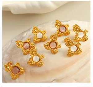 Macro detail of wavy gold flower earrings with pink and white cat eye stones