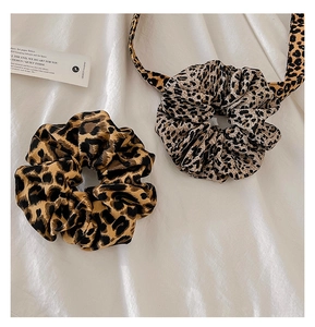 Detailed set of leopard print hair scrunchies and matching headband on white silk
