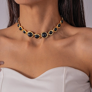 Detail of vintage gold choker necklace with black resin stone on a female model